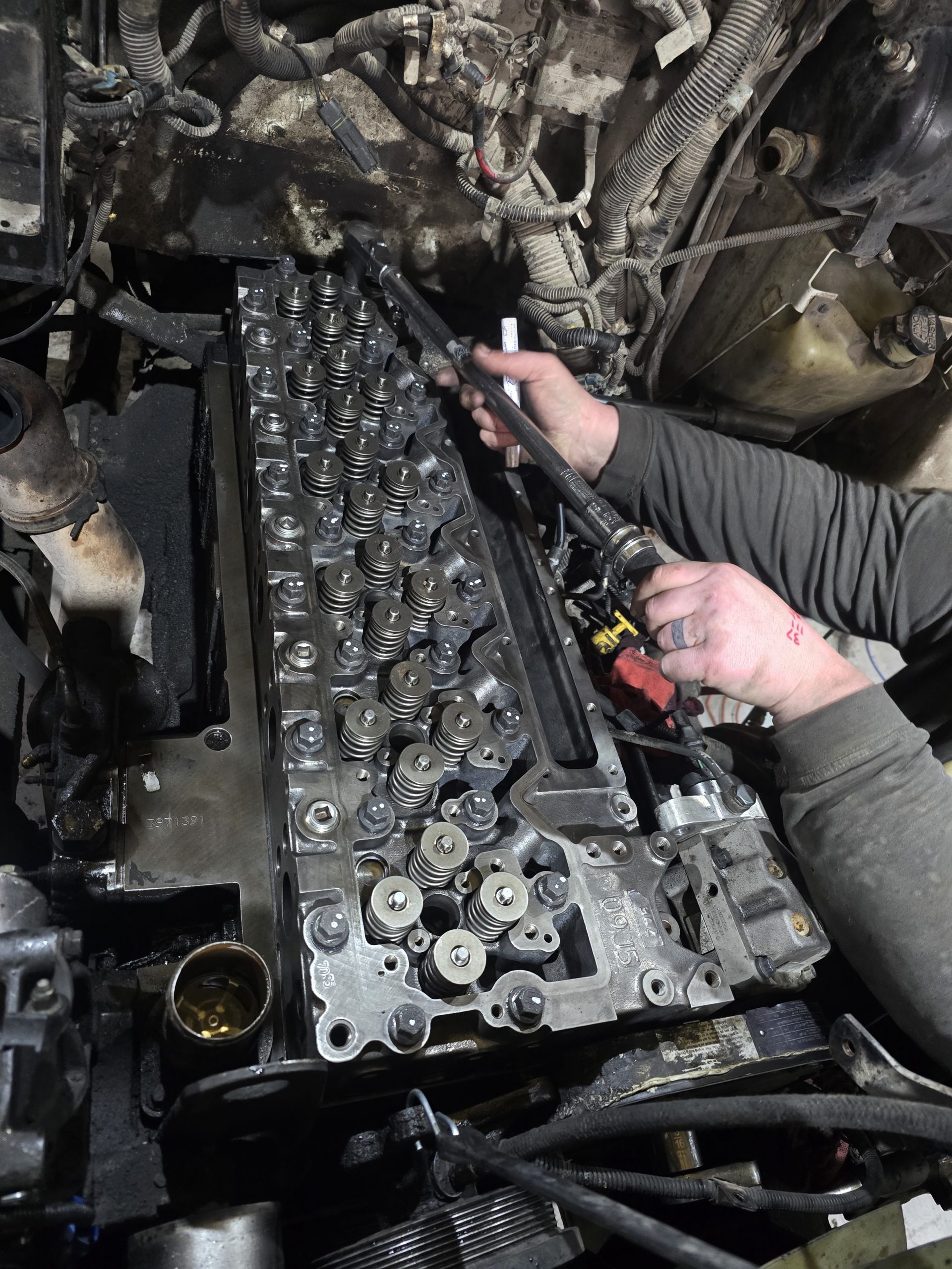 Technician working with a torque wrench on an exposed diesel cylinder head at Burnside